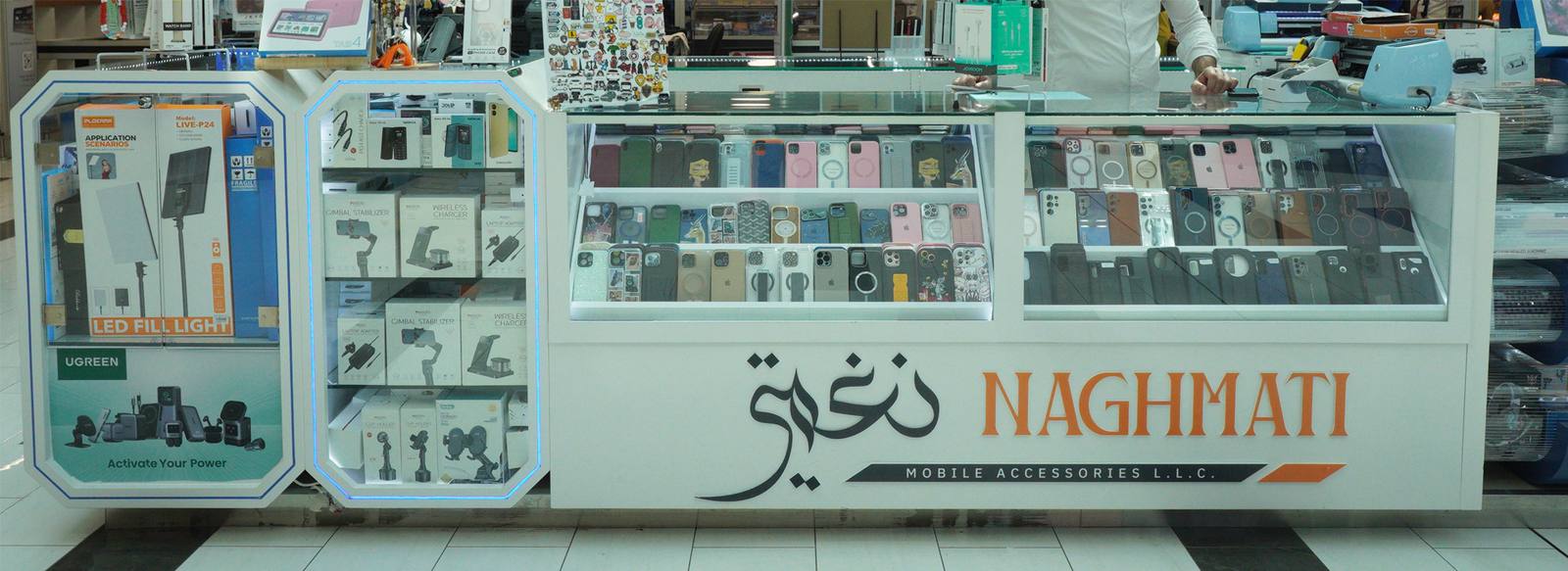 The Naghmati kiosk in Forsan Central Mall: glass cabinets of cases and chargers with the NAGHMATI name on the front